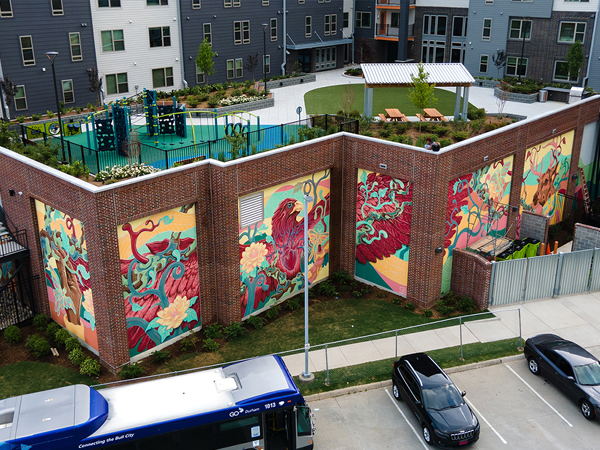 Photograph of a raised plaza, two stories up from street level, decorated with muraled stucco panels.