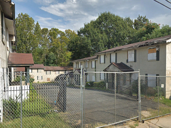 Photograph of former two-story residential structures with windows boarded.