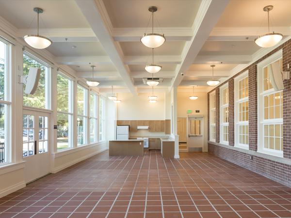 Picture of a largely empty communal space with a kitchen. 