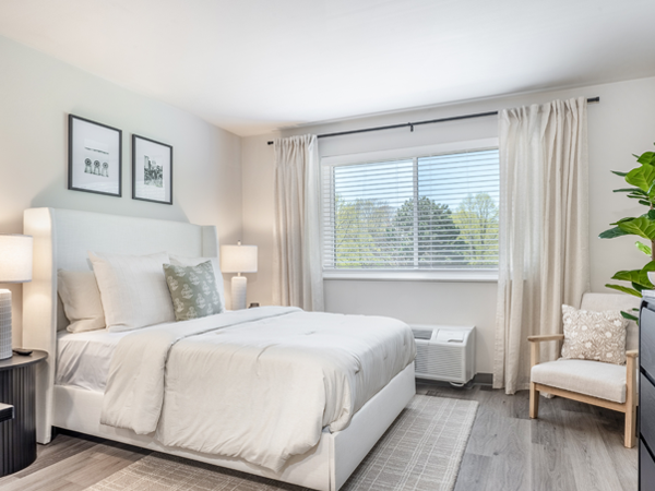 An apartment bedroom furnished and decorated in neutral tones.