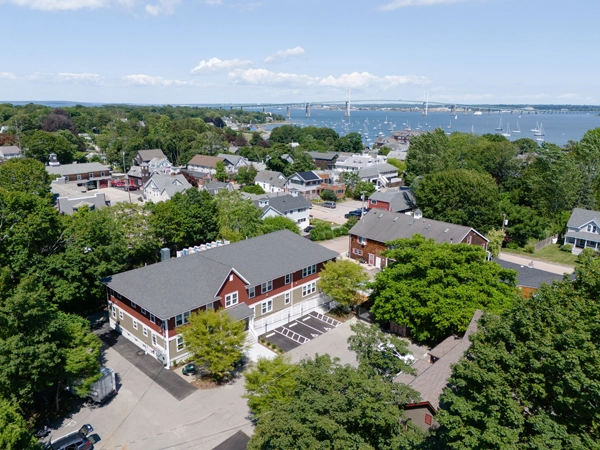 Aerial photograph of a two-story apartment building in a seaside town.