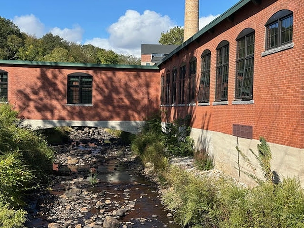 Exterior of a brick building with an archway above a stream.