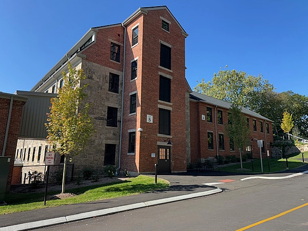 Exterior of a large brick building with a road in the foreground.