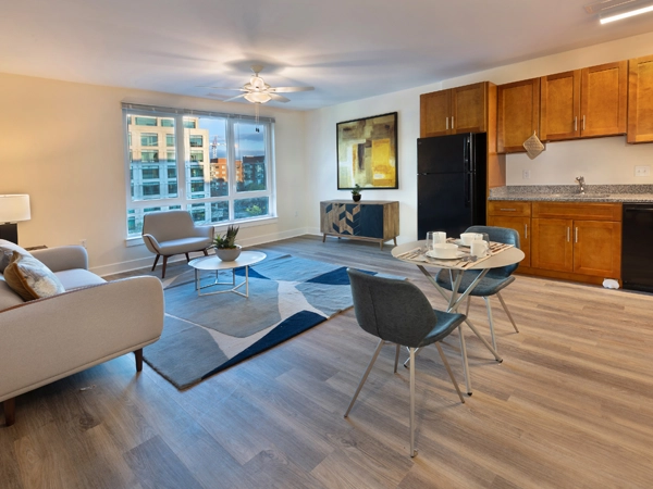 An apartment living room with vinyl plank flooring and a kitchenette.