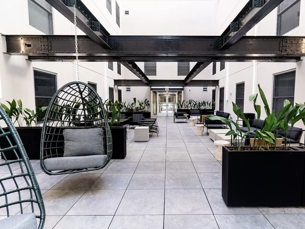 A paved interior courtyard with stone flooring, rectangular planters, hanging chairs, and outdoor seating and tables.