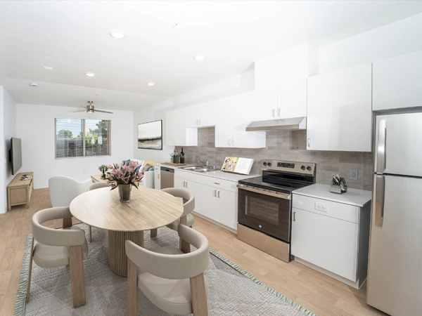 A modern, airy living room and kitchen with granite countertops and hard-surface flooring.
