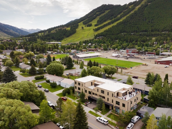 Aerial view of a three-story condominium building in a mountainous area.