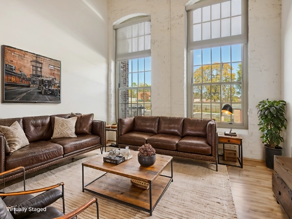 Interior photo of a loft-style apartment in a converted mill building, with two large windows.