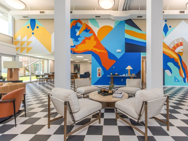 A brightly decorated community space with seating areas, tiled floors, and colorful wall murals.