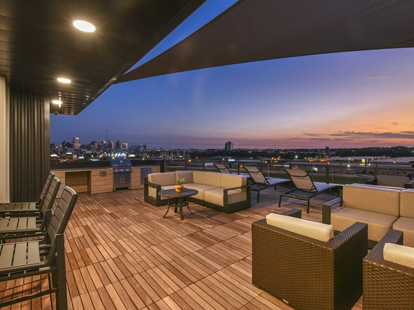 A furnished rooftop terrace at dusk with a view of an urban downtown.