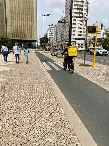 Photo of a cyclist on a bicycle path, and pedestrians to the left of the path.