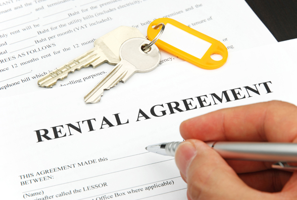 Close up of a hand signing a form with the words "Rental Agreement."