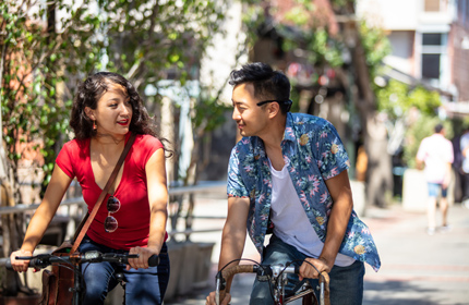 A man and a woman riding their bicycles side by side.