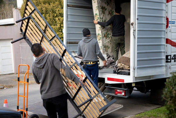 Three people loading furniture into a moving truck.