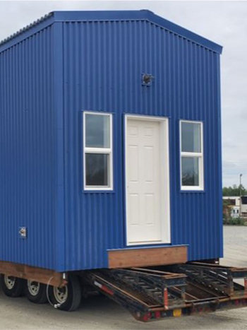 Photo of blue tiny home mounted on a trailer.