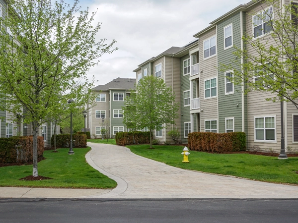 An apartment complex, with a sidewalk cutting through the middle and houses to the left, right, and back.