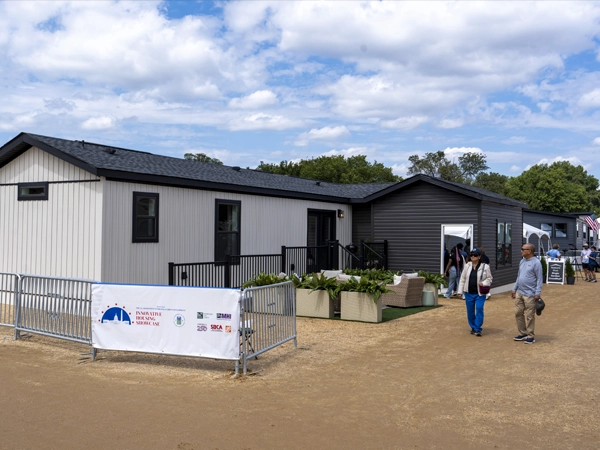 A model house on display with a group of people walking nearby.