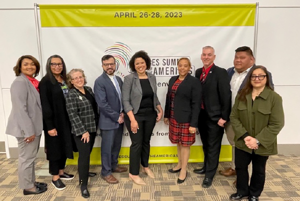 A group of people stand in front of a banner for the Cities Summit.