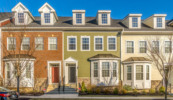 Photograph of the front façades of three 2-story townhouses with a bay window next to the front door.