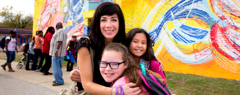 Photograph of three people in front of a mural in the Covington neighborhood.