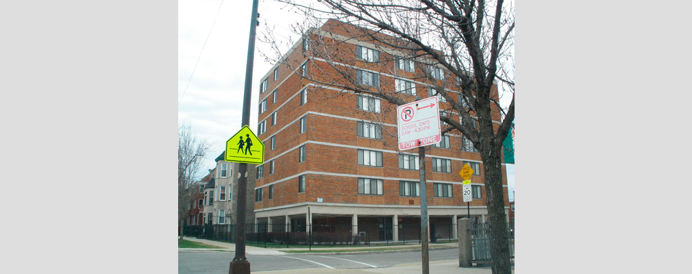 Photograph of the front and side façades of a renovated seven-story multifamily building.