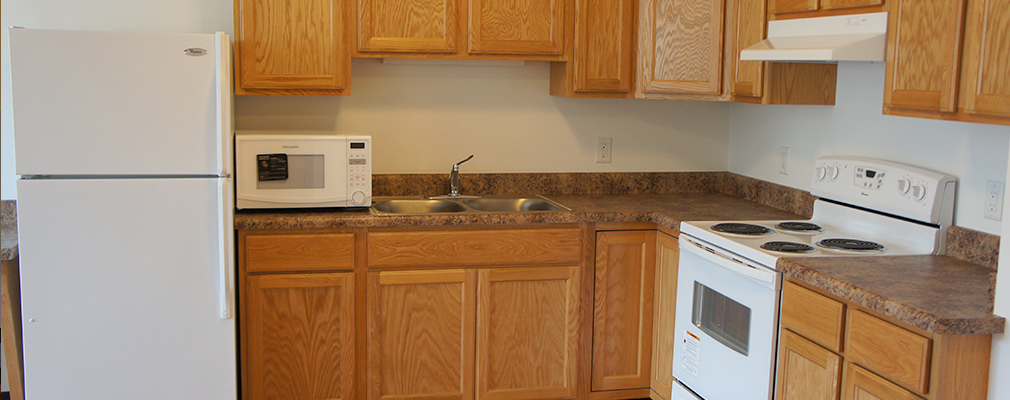 Photograph of a kitchen area with a refrigerator, oven, and microwave.