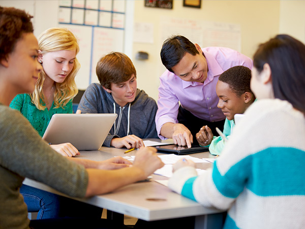 Image of teacher assisting six students in a classroom. Image of teacher assisting six students in a classroom.