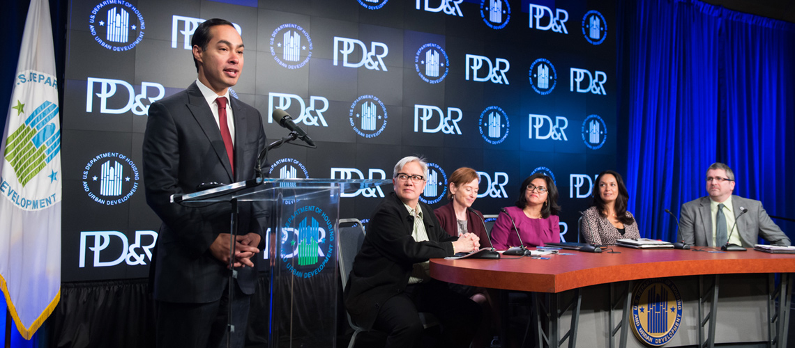Photograph of HUD Secretary Julián Castro speaking at a podium in front of a background with the PD&R logo.