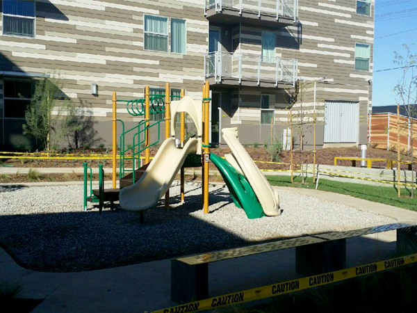 Photograph of a playground adjacent to a multistory residential building.