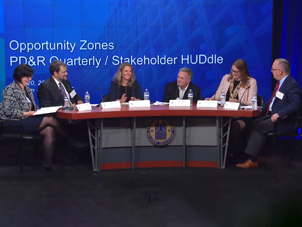 Moderator Erika Poethig, and panelists (left to right) Michael Kressig, Rachel Reilly, Frank Dickson, Fran Seegull, and Robert Stoker, sit at a table on stage in front of a banner stating “Opportunity Zones PD&R Quarterly/Stakeholder HUDdle.” Moderator Erika Poethig, and panelists (left to right) Michael Kressig, Rachel Reilly, Frank Dickson, Fran Seegull, and Robert Stoker, sit at a table on stage in front of a banner stating “Opportunity Zones PD&R Quarterly/Stakeholder HUDdle.”