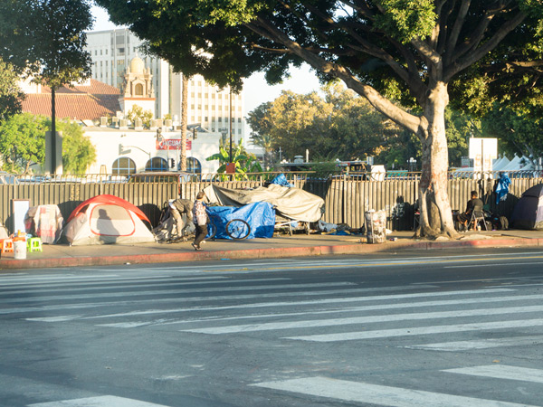 Tents line the sidewalk along a street in Los Angeles, California. Tents line the sidewalk along a street in Los Angeles, California.