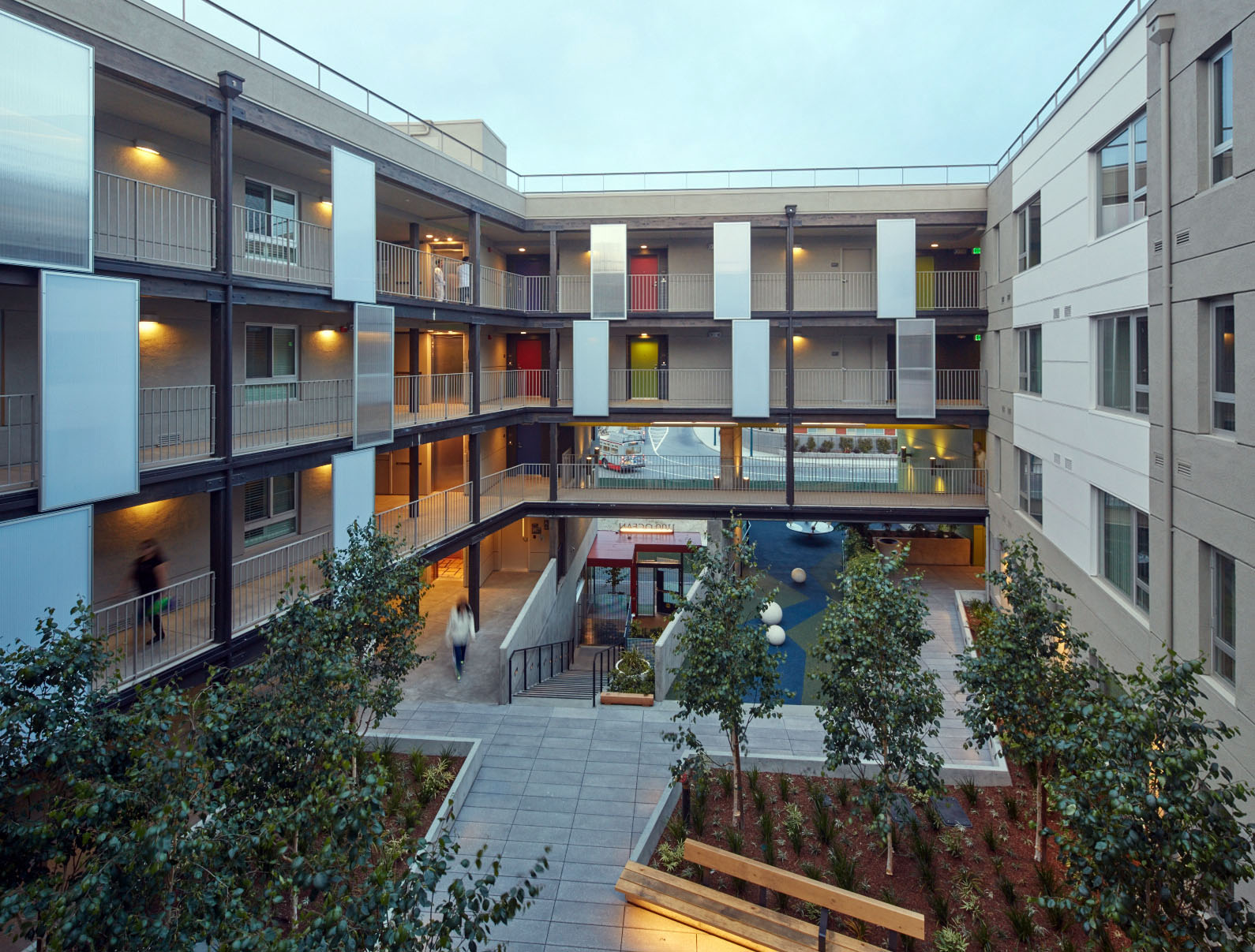 Photograph of a landscaped courtyard, surrounded by walkways and residential units. Photograph of a landscaped courtyard, surrounded by walkways and residential units.