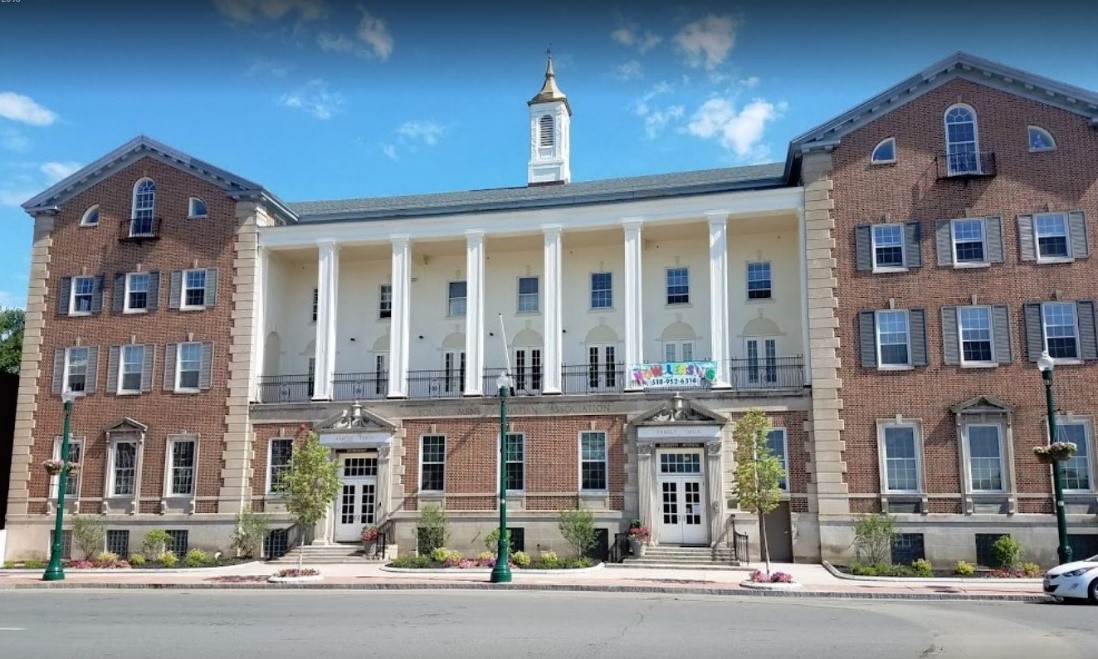 The façade of the multistory Capital YMCA building, featuring columns lining the balcony above the first floor. The façade of the multistory Capital YMCA building, featuring columns lining the balcony above the first floor.