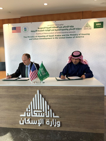 U.S. Assistant Secretary for Policy Development and Research Seth D. Appleton and Saudi Arabia’s Minister of Housing Majid Al-Hogail sit at a desk displaying the two countries’ flags and sign documents.