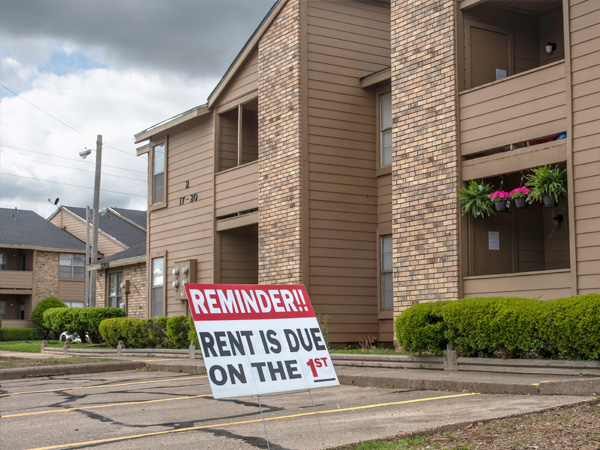 An apartment with a sign in front reminding residents about the rent.