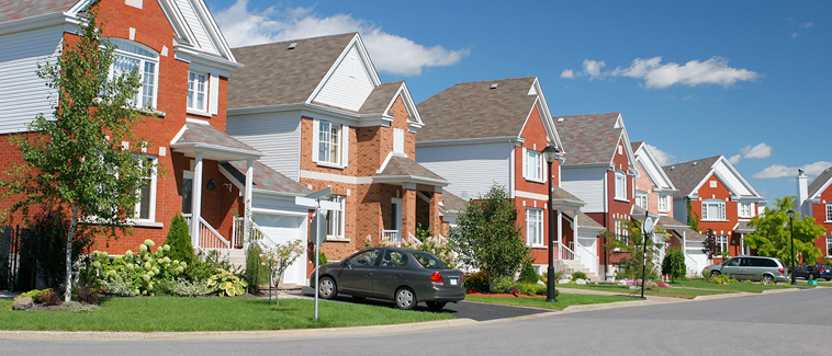 Photograph of several multi-story, single-family, detached homes along a road. 