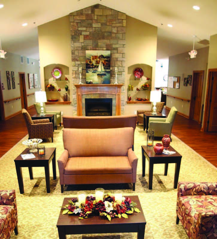 A large room with high, angled ceilings, a fire place, and seating areas.