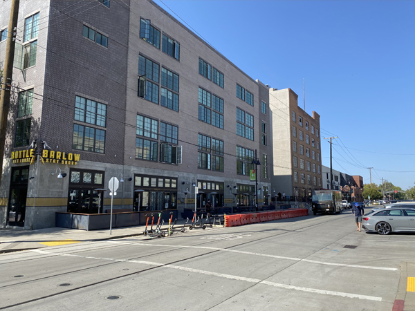 Photograph of the exterior of a four-story building and a road with a crosswalk and street parking. Photograph of the exterior of a four-story building and a road with a crosswalk and street parking.