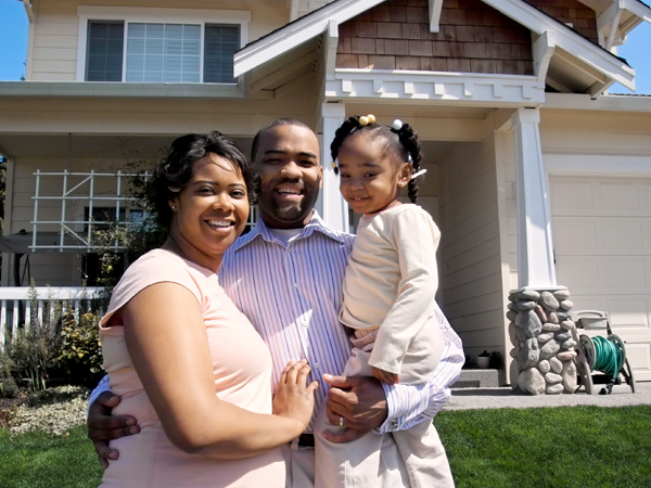 Photo of a family standing in front of a house. Photo of a family standing in front of a house.