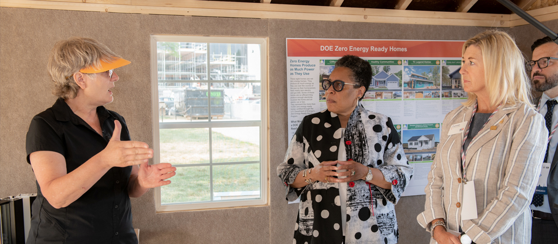 Three people listening to an exhibitor speak inside a model home Three people listening to an exhibitor speak inside a model home