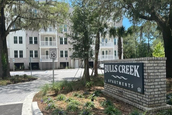 Apartment building with landscaping and large “Bulls Creek Apartments” sign in front.
