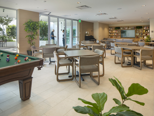  Image of a common room with tables and chairs, a pool table, and television.