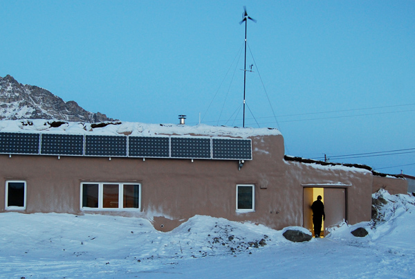 A single-story home with solar panels, surrounded by snow.